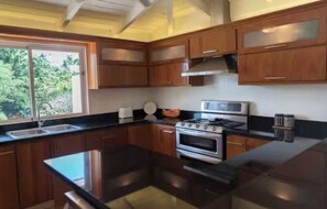 A modern kitchen with wooden cabinets, a stainless steel stove, and a large island. - Luxurious 4-Bedroom Villa with Private Pool in La Romana (La Romana city)
