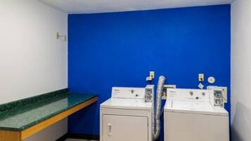 A laundry room with two white washing machines, a blue wall, and a green countertop.