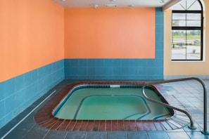 Una piscina con borde de azulejos, baranda de metal y vista al exterior a través de una ventana.
