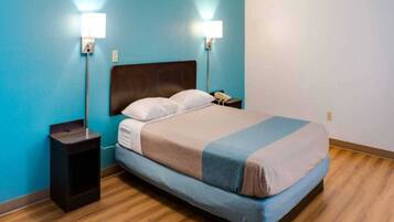A hotel room with a bed, two bedside lamps, a nightstand, and a phone.