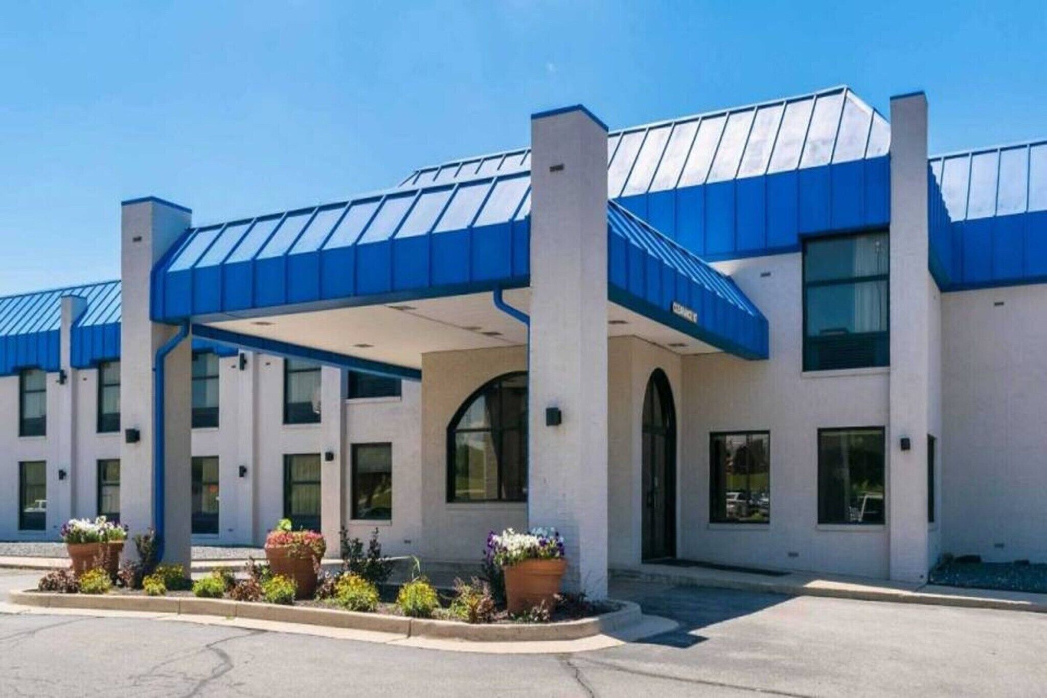 A hotel with a covered entrance, multiple windows, and potted plants in the foreground.