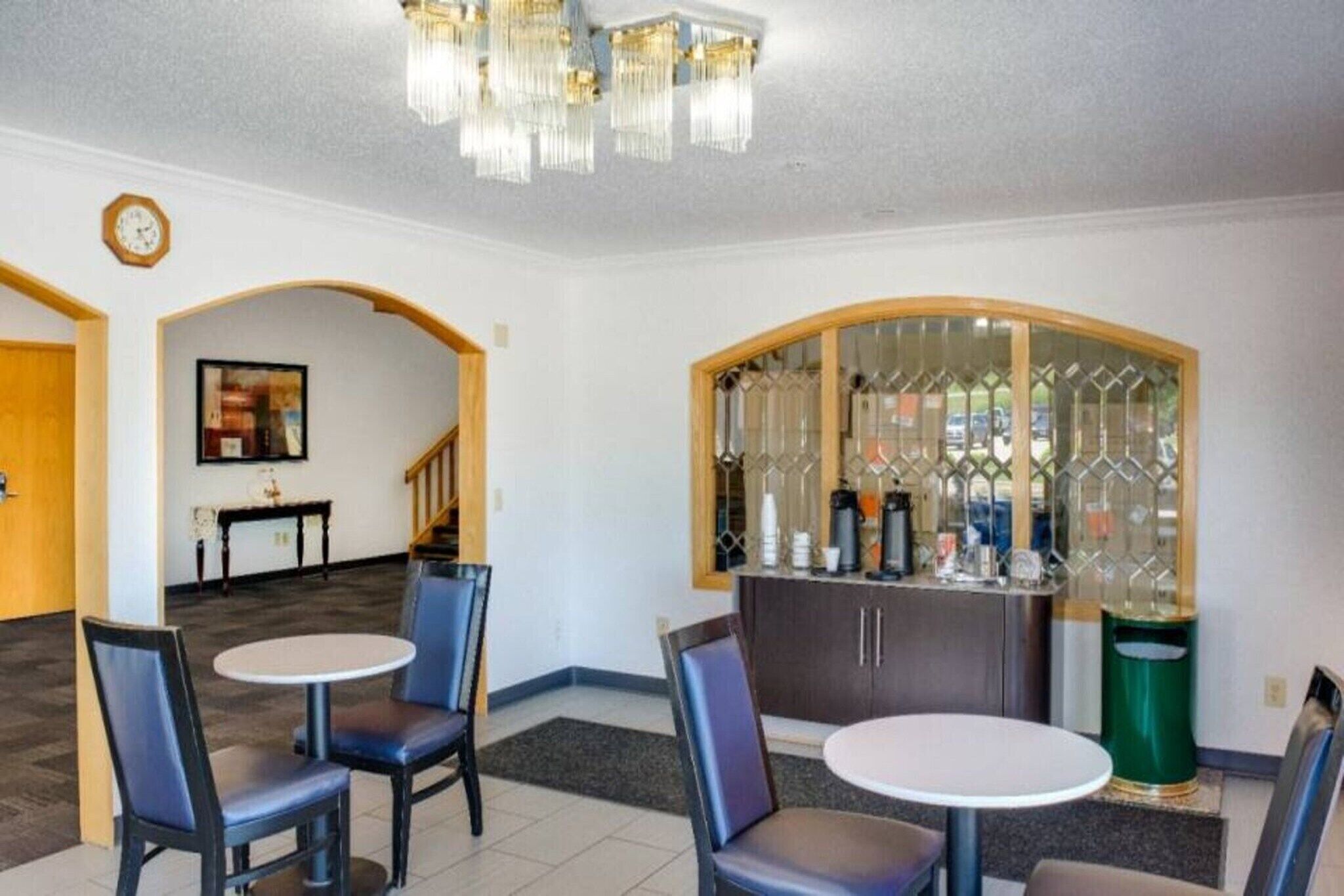 Un vestíbulo de hotel con zona de bar, asientos y una escalera.