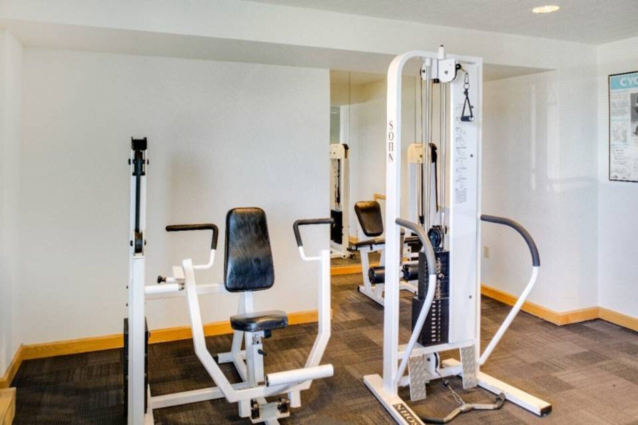 Un gimnasio con equipo de ejercicio, incluyendo una máquina para piernas y una prensa de pecho.