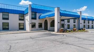 A hotel with a blue roof, a parking lot, and a clear sky.