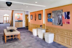 A hotel lobby with a reception desk, a staircase, and a seating area with a table and chairs. - 1 King Bed | Non-Smoking (Richmond IN)
