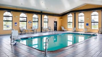 A large indoor swimming pool with multiple lounge chairs and a changing room.