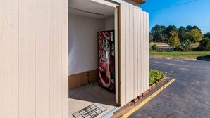 Un edificio con una puerta abierta que muestra una máquina expendedora en su interior.