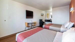Habitación de hotel con dos camas, un escritorio, una silla, un televisor y una kitchenette.