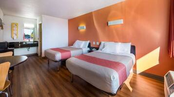 Een hotelkamer met twee bedden, een eethoek en een kitchenette.