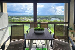 A balcony with a table and chairs, overlooking a river and greenery. - 'The Wake Zone' Condo Near Lake of the Ozarks (Lake Ozark)