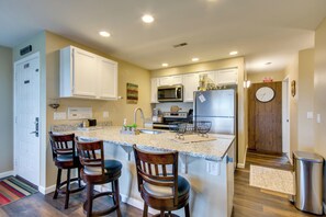 A modern kitchen with a central island, bar stools, a microwave, and a refrigerator. - 'The Wake Zone' Condo Near Lake of the Ozarks (Lake Ozark)