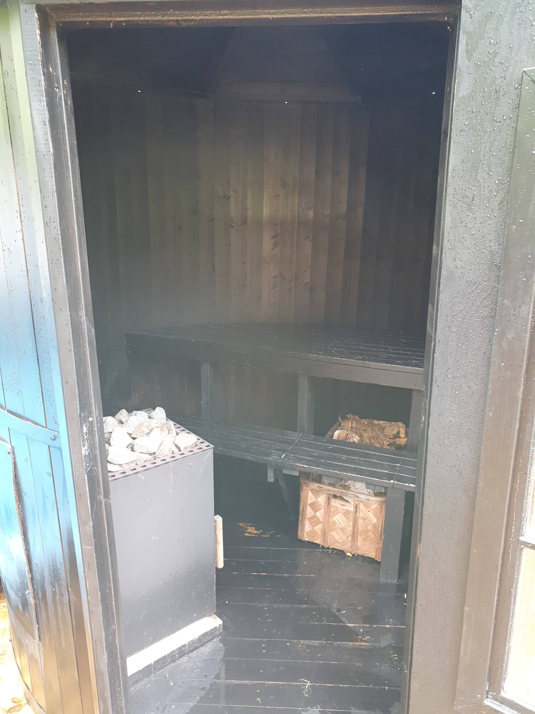 A room with a black floor, a wooden door, and a metal shelf unit.