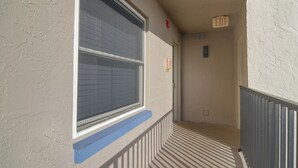 A corridor with a window, an exit sign, and a radiator. - Unit w/ Stunning Gulf Views! Steps to Pool & Beach (Madeira Beach)