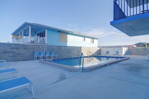 Ein Poolbereich mit einem kleinen Gebäude, Liegestühlen und einer Betonplattform.
