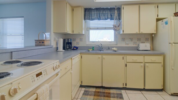 A kitchen with a stove, sink, and cabinets. - Unit w/ Stunning Gulf Views! Steps to Pool & Beach (Madeira Beach)