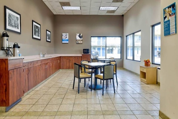 A clean, well-lit kitchen area with a wooden counter, a sink, and a dining table with chairs.