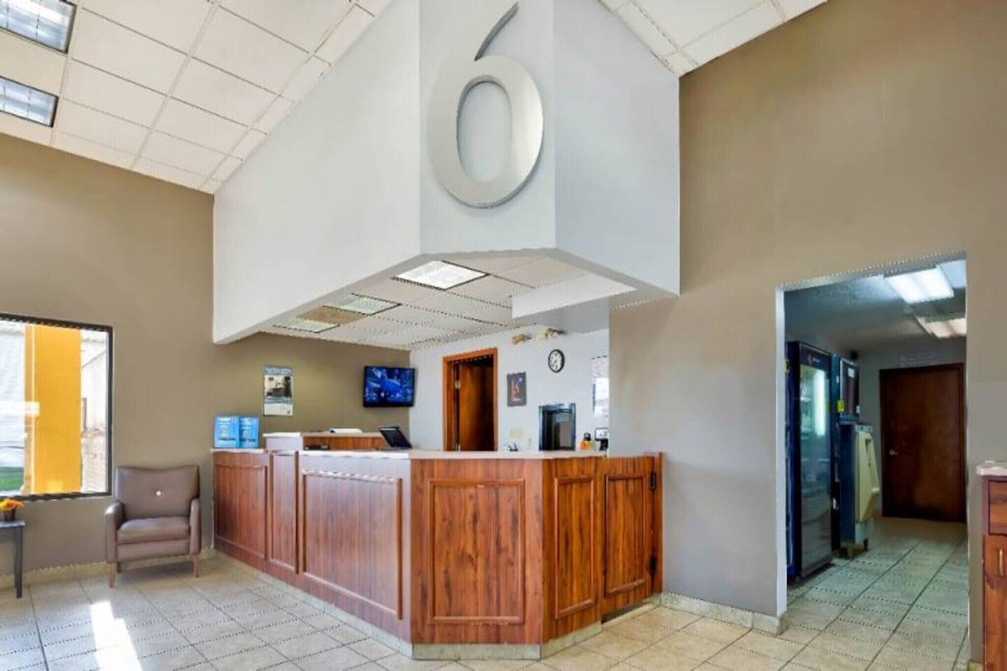 A reception area with a wooden counter, a clock, and a television.