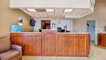 A reception area with a wooden reception desk, a brown leather couch, and a tiled floor.