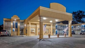 A hotel entrance with a covered waiting area, a flag, and a parking lot. - 2 Queen Beds | Non-Smoking, Micfridge (Effingham)