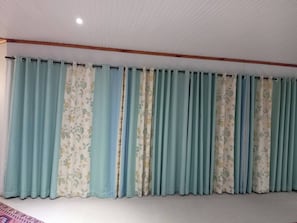 A room with a large window covered by multiple curtains.
