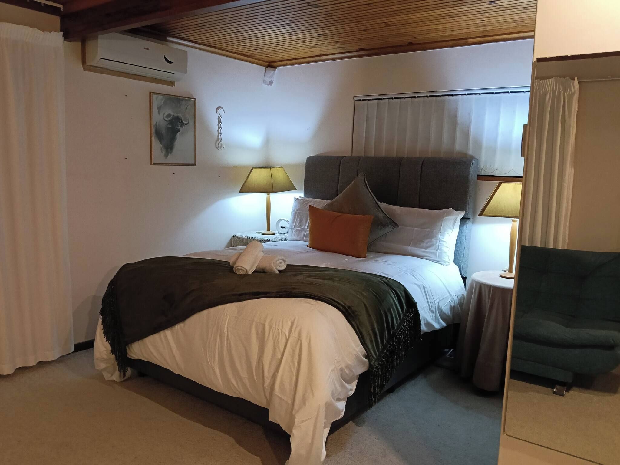 Une chambre d’hôtel avec un lit, deux lampes de chevet, une table de chevet, une chaise et une fenêtre avec des rideaux.