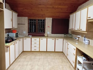 A kitchen with wooden cabinets, a window with blinds, and a tiled floor.