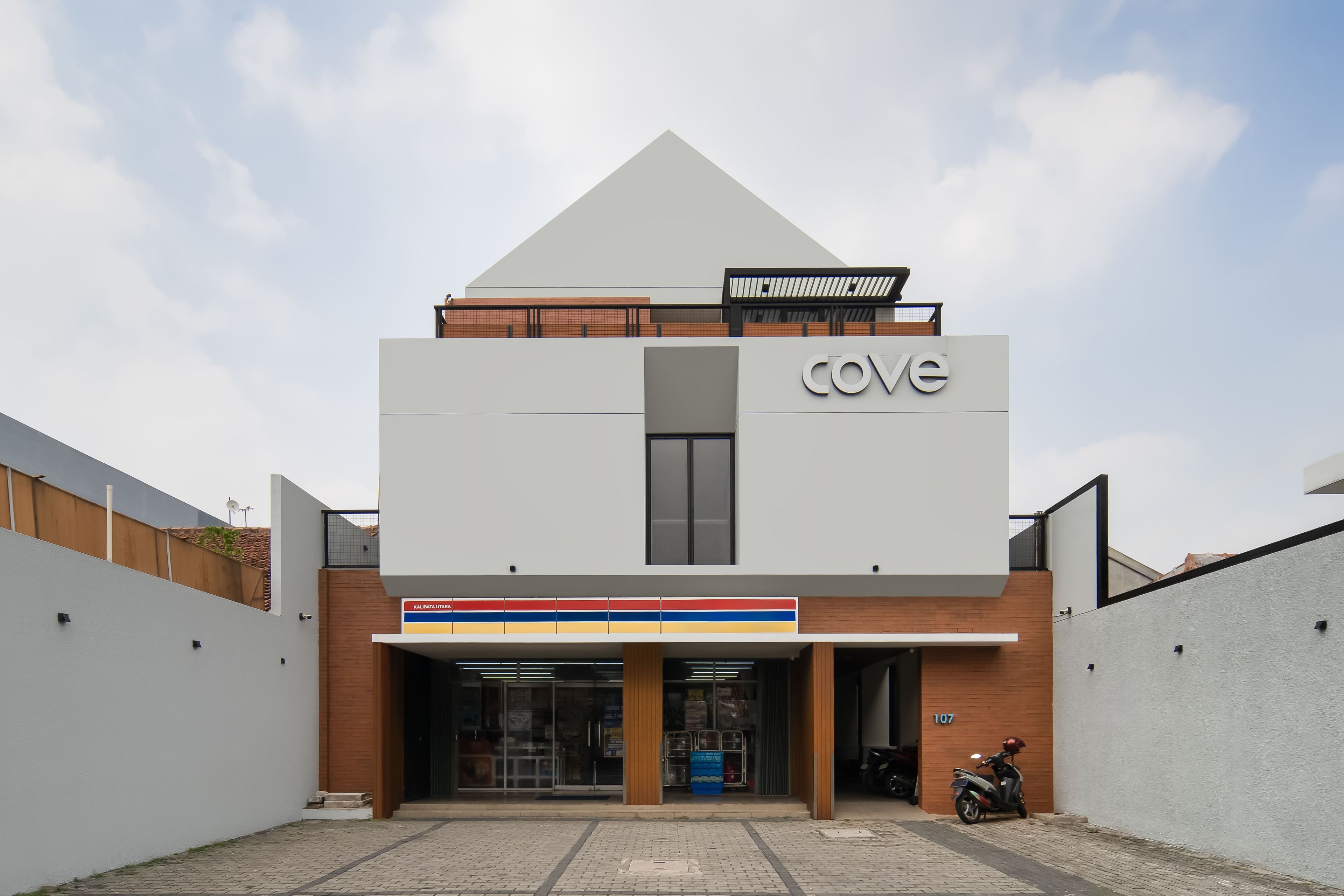 A modern building with a prominent 'cove' sign, a covered entrance, and a motorcycle parked outside.