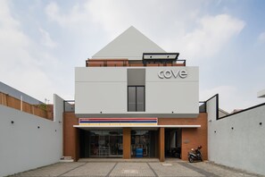 Een modern gebouw met een opvallend ‘cove’ bord, een overdekte ingang en een motorfiets voor de deur.