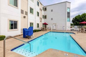 A swimming pool with a tiled edge, surrounded by lounge chairs and umbrellas, with a building in the background. - 2 Full Beds | Non-Smoking, Micfridge (Caseyville)