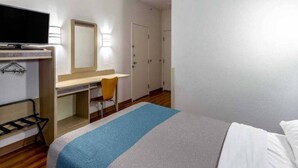 Hotellihuone, jossa on sänky, työpöytä, tuoli, televisio ja vaatekaappi.