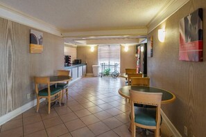 A dining area with a kitchen in the background, a bicycle, and a trash can. - 1 KING BED | SUITE NON-SMOKING (Grand Prairie)