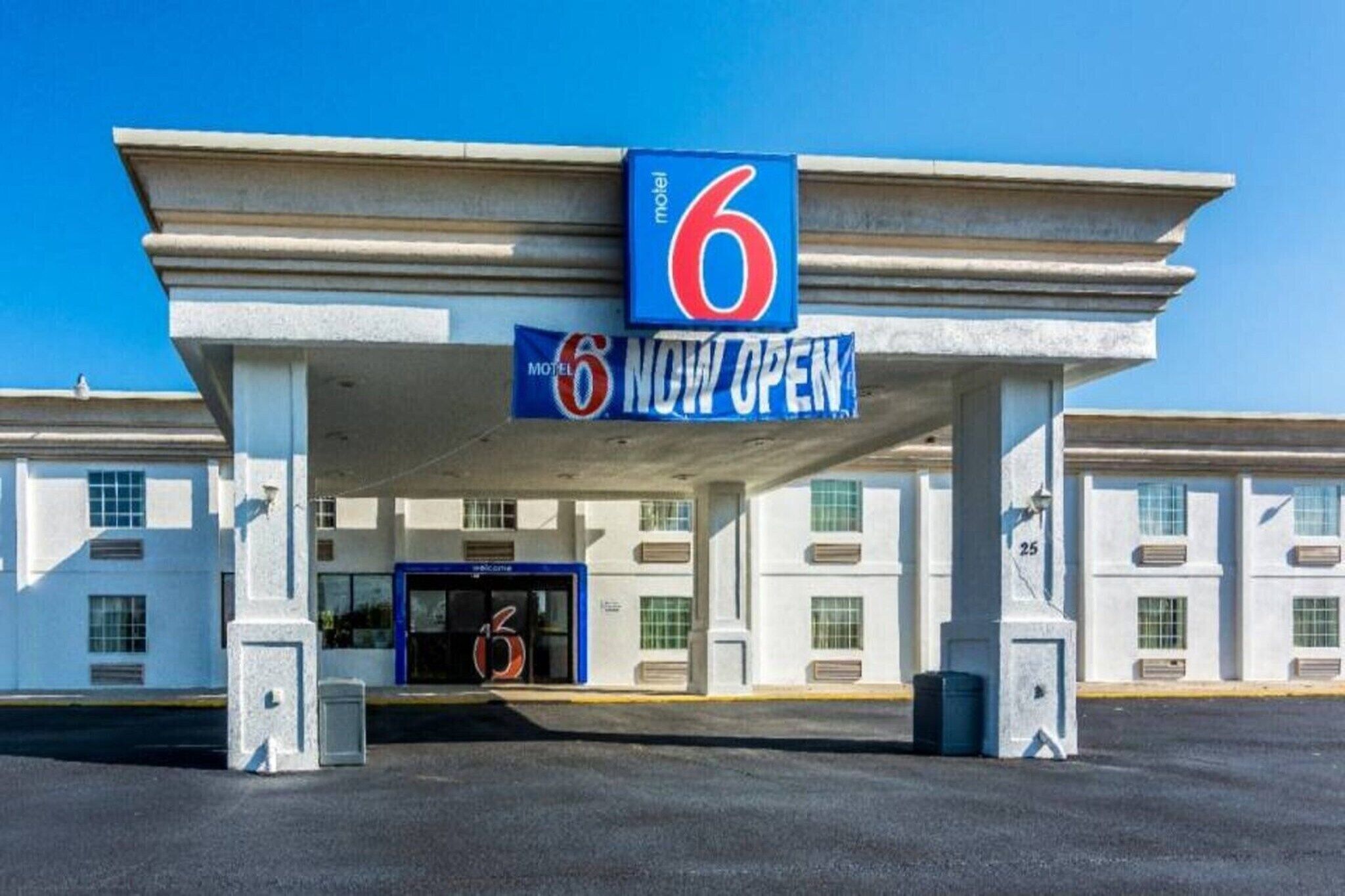 Een motel met een opvallend bord met het cijfer '6' en een 'NU OPEN' banner.