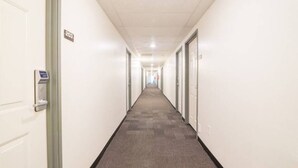 Passadís llarg i estret d'un hotel, amb portes a banda i banda, terra amb moqueta i sostre amb il·luminació empotrada.