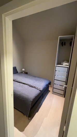 A bedroom with a bed, a nightstand, and a wardrobe.