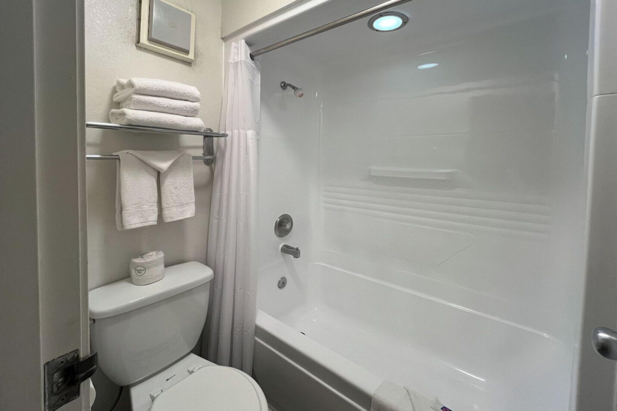Une salle de bain équipée de toilettes, d’une douche et d’un porte-serviettes avec des serviettes pliées.