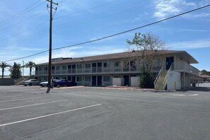 Un motel con una struttura su due piani, un parcheggio e una scala che conduce all'ingresso.