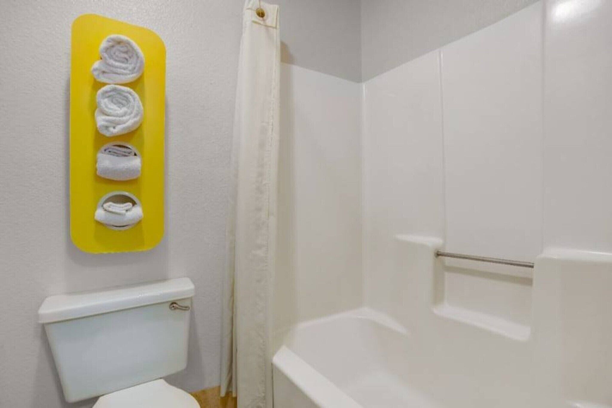 A bathroom with a toilet, a shower stall, and a towel rack with folded towels.