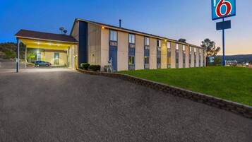 A motel with a single-story building, a covered parking area, and a well-maintained lawn.