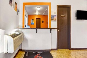 Un espace d’accueil d’hôtel comprenant un comptoir de réception, une horloge et une porte portant l’inscription « RESERVÉ AU PERSONNEL ».