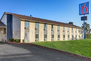 Un motel avec une série de chambres, un parking et une zone herbeuse.