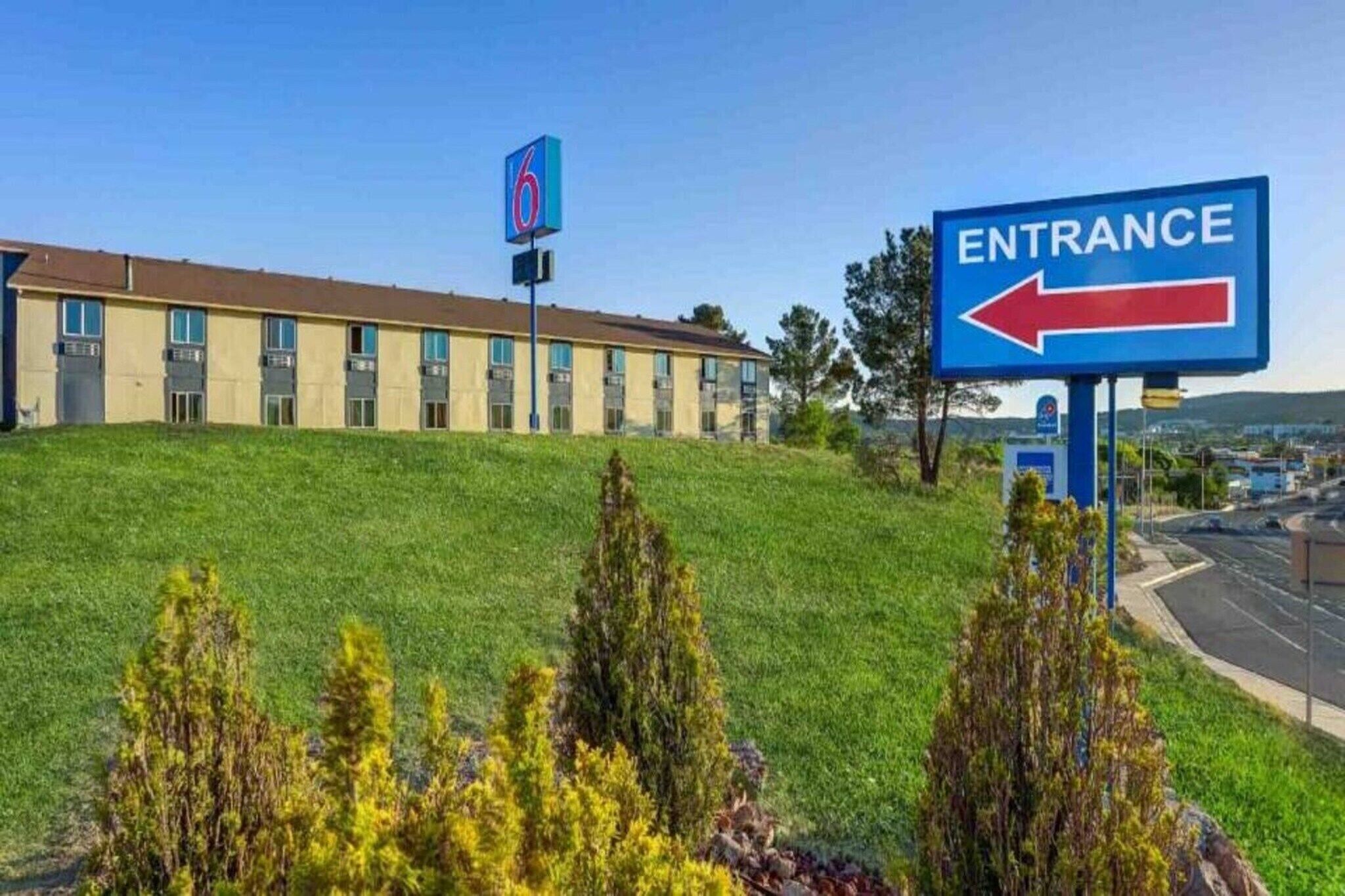 A building with a sign indicating an entrance and a motel sign in the background.
