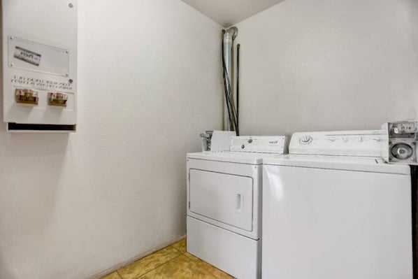 A laundry room with a washing machine and dryer, a utility meter, and a water heater.