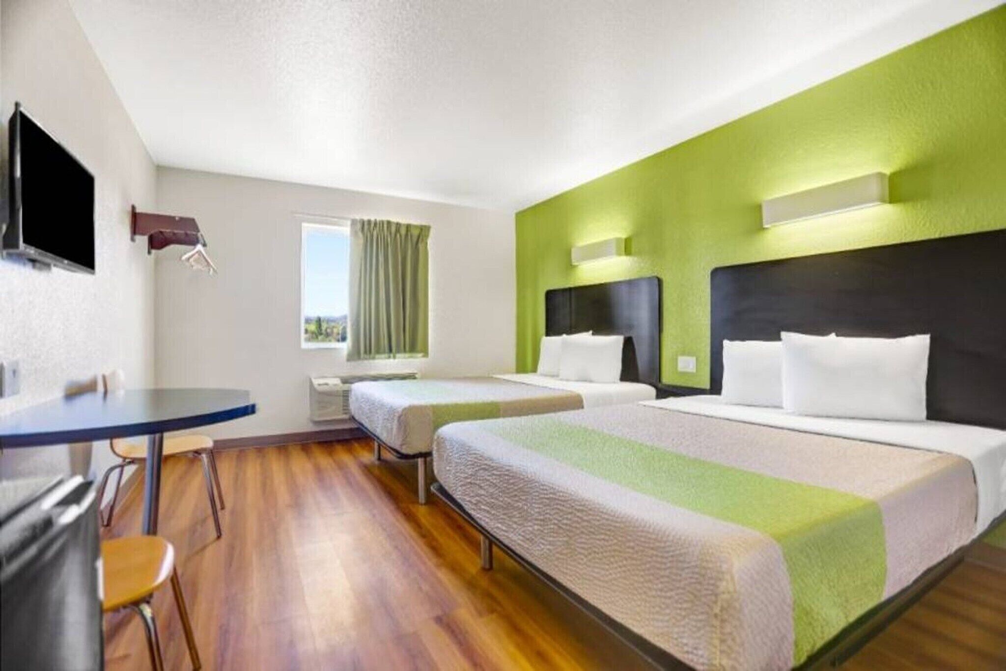 A hotel room with two beds, a desk, and a chair.