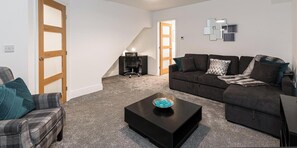 A living room with a sofa, armchair, coffee table, and a staircase leading to another room. - 7 Tannery House | Wi-Fi | Parking | Contractors (Freckleton)
