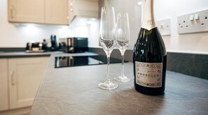 Una ampolla de vi Prosecco i dues flautes de vi buides sobre una cuina.