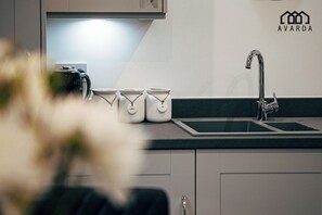 A kitchen with a modern faucet, a sink, and three jars labeled 'milk,' 'coffee,' and 'tea.' - 7 Tannery House | Wi-Fi | Parking | Contractors (Freckleton)