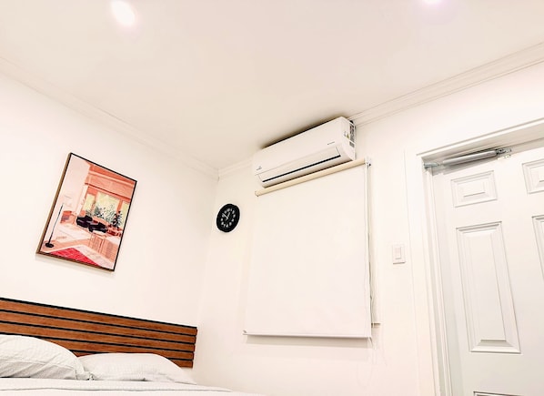 Une chambre à coucher avec un lit, un appareil de climatisation, une horloge et une porte.