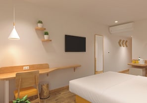 A hotel room with a bed, a desk, a chair, a TV, a mirror, and a shelf with plants. - Bloom Hotel Chembur (Mumbai)