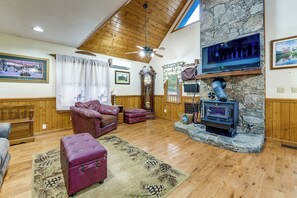 Ein gemütliches Wohnzimmer mit Kamin aus Stein, Ledermöbeln und einem an der Wand montierten Fernseher.