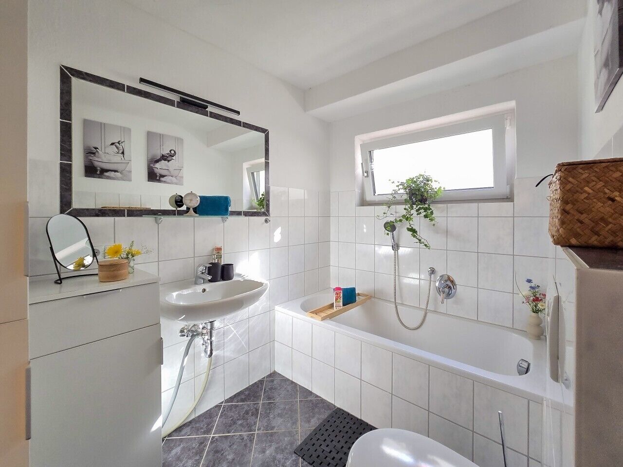 A modern bathroom with a white sink, a mirror, a bathtub, and a shower.